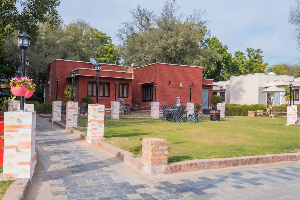 Red brick cottages with garden seating area at Thar Exotica resort in Bikaner