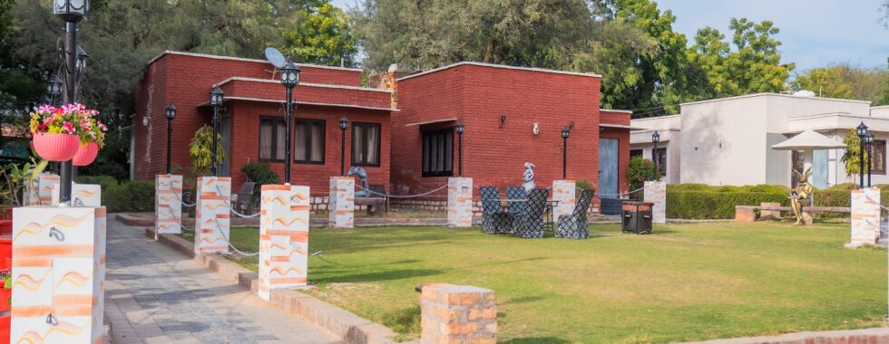 Red brick cottages with garden seating area at Thar Exotica resort in Bikaner